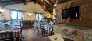 ein Restaurant mit Tischen und Stühlen und einem Flachbildfernseher in der Unterkunft Cà Praudin in Vico Canavese