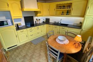 une cuisine avec des armoires jaunes et une table en bois dans l'établissement Gîte Pachamama, à Cayeux-sur-Mer