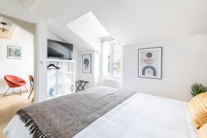 a white bedroom with a large bed and a chair at LIK APPARTS MABILAY in Rennes