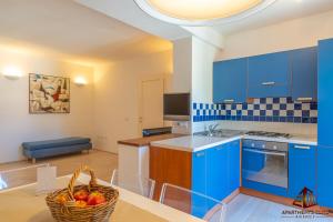 a kitchen with blue cabinets and a table with a basket of fruit at Porto Rotondo Central House in Porto Rotondo