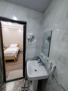 a bathroom with a sink and a mirror and a bed at Hanifa Boutique in Samarkand