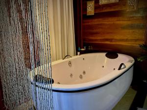 a white bath tub in a bathroom with a curtain at Pousada Riacho Dos Cambucas in Abraão