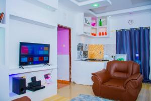 a living room with a chair and a flat screen tv at CRYSTAL HOMES Air BnB in Mumias