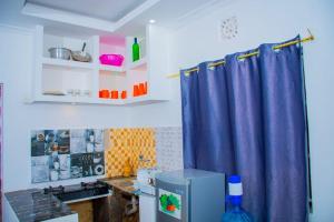 cocina con cortina azul y nevera en CRYSTAL HOMES Air BnB, en Mumias