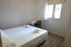 a white bedroom with a bed and a window at Vacare centro de Santander in Santander