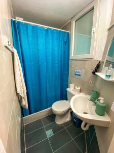 a bathroom with a blue shower curtain and a toilet and sink at Sea View Studio Armenistis Ikarias No2 in Armenistis