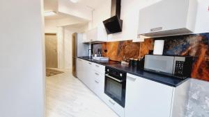 a kitchen with white cabinets and a black counter top at Apartamenty Startowa 4A in Gdańsk