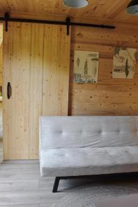 um sofá branco num quarto com paredes de madeira em Tiny Heaven Cabin em Călimăneşti