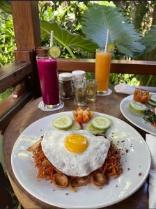 un piatto di cibo con un uovo e funghi su un tavolo di Aix Cottage Ubud ad Ubud