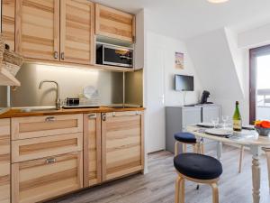 a kitchen with wooden cabinets and a table with chairs at Apartment Le Grand Cap-15 by Interhome in Villers-sur-Mer