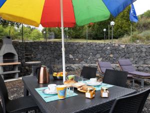 a table with a colorful umbrella and food on it at Holiday Home Alcunché by Interhome in Zafferana Etnea