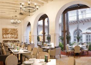 un restaurante con mesas, sillas y ventanas grandes en Casa Pestagua Relais Châteaux, en Cartagena de Indias