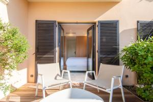 two chairs and a table on a patio with a bedroom at Hotel Brin d'Azur - Saint Tropez in Saint-Tropez