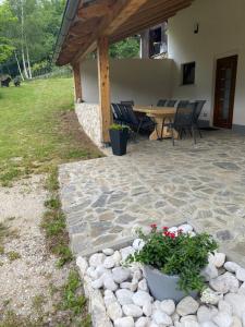 a patio with a table and chairs and flowers at Posestvo Tmžek in Bovec