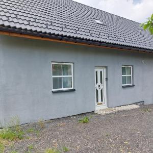 ein graues Haus mit einer weißen Tür und Fenstern in der Unterkunft Szary domek 1 in Wieprz