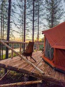 a tent and a chair on a wooden deck at Glamping Laenlammen tila in Rovaniemi