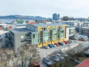 a large yellow building with cars parked in a parking lot at Laugavegur Penthouse in Reykjavík