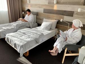 a man and woman sitting on beds in a room at Hotel Sisimiut in Sisimiut