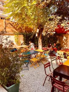 een groep tafels en stoelen op een patio met een boom bij YASI Hostel in Lyon
