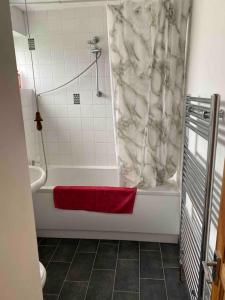 W łazience znajduje się wanna, prysznic i czerwony ręcznik. w obiekcie Charlie’s House Newmarket w mieście Newmarket