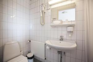 a white bathroom with a toilet and a sink at Hotel Sisimiut in Sisimiut