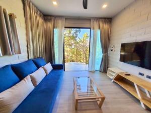 a living room with a blue couch and a glass table at Villa PaSon in Khao Kho