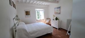 a white bedroom with a bed and a window at Canapali in Longoio