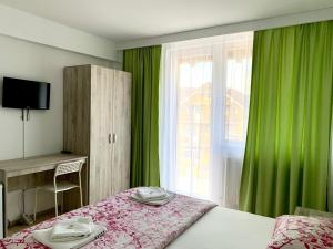 a bedroom with a bed and a window with green curtains at Pensiunea ALAS in Baile Felix