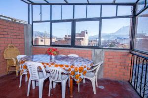einen Tisch und Stühle in einem Zimmer mit Fenstern in der Unterkunft CAYESH Guest House in Huaraz