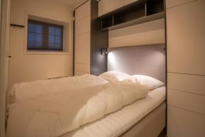 uma cama com lençóis brancos e almofadas num quarto em Høyfjellsgrend 961, 29 B em Trysil