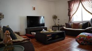 a living room filled with furniture and a flat screen tv at riad casa bahia asilah in Asilah
