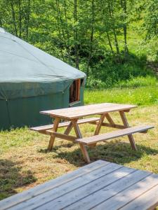 - une table de pique-nique en bois devant une tente dans l'établissement Yourtissimo, à Laprugne