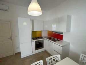 a kitchen with white cabinets and a stove top oven at La Torre Apartment by My Home Apulia in Torre Lapillo