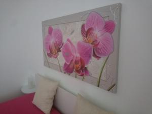 a painting of pink orchids on a wall at La Torre Apartment by My Home Apulia in Torre Lapillo