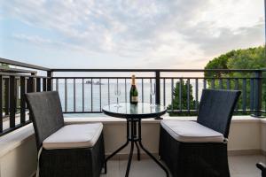 Mar Azul Apartments Petrovac في بتروفاتس نا مورو: شرفة مع طاولة وكرسيين وزجاجة من النبيذ