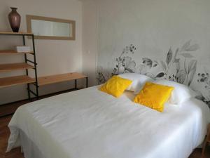 - une chambre avec un lit blanc et 2 oreillers jaunes dans l'établissement Gîte privatif, proche nature et plan d'eau, à Charlanges