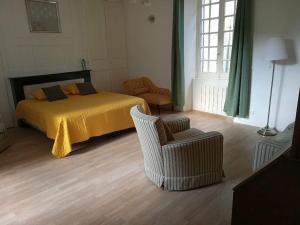 ein Schlafzimmer mit einem Bett mit einer gelben Decke und einem Stuhl in der Unterkunft Gîte privatif, proche nature et plan d'eau 
