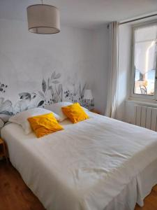 Una cama blanca con almohadas amarillas en un dormitorio en Gîte privatif, proche nature et plan d'eau 