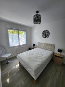 1 dormitorio con cama blanca y ventana en Appartement vue mer en Saint-Georges-de-Didonne