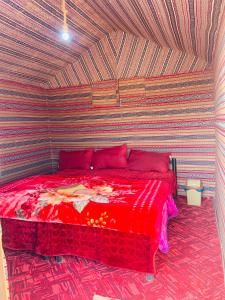 a bedroom with a red bed with a striped wall at Wadi Rum Bedouin Heart Camp in Wadi Rum