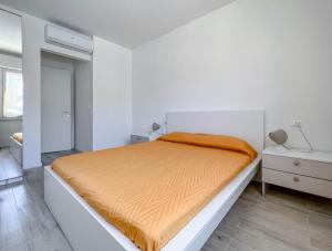 una camera da letto bianca con un letto e una coperta arancione di Nuovo Bilocale con posto auto a Varazze