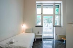 ein weißes Schlafzimmer mit einem Bett und einem Fenster in der Unterkunft LightBox Central in Ljubljana
