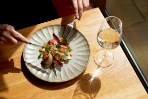沃明斯特Bishopstrow Hotel and Spa - Small Luxury Hotels of the World的用叉子和刀子切一盘食物的人