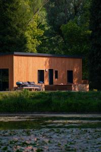 a small wooden building with a picnic table in front of a lake at Le Nichoir du Marais - écolodge in Ponts-et-Marais