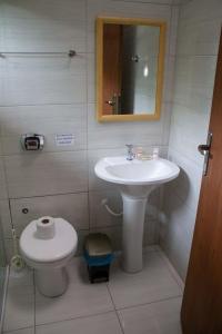 a bathroom with a sink and a toilet and a mirror at Pousada GaropaSul in Garopaba