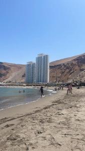 a beach with people playing in the water and buildings at Departamento frente al mar en Arica in Arica