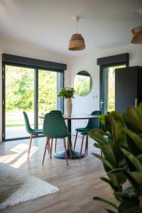 a dining room with green chairs and a table at Le Nichoir du Marais - écolodge in Ponts-et-Marais +23 photos