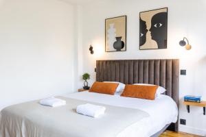 - une chambre avec un grand lit blanc et des oreillers orange dans l'établissement LIK APPARTS Thabor, à Rennes