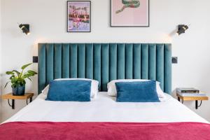 - une chambre avec une tête de lit verte et un lit avec des oreillers bleus dans l'établissement LIK APPARTS Thabor, à Rennes
