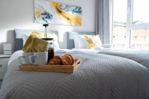 a tray of croissants and coffee on a bed at Century Central, Cardiff Bay, Modern Chic 2BR, Free Parking in Cardiff